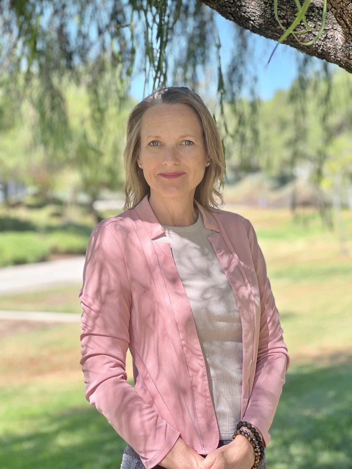 Denise Frisella standing beneath a willow tree
